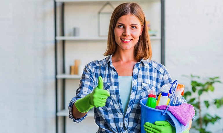 Schoonmaakmedewerker met emmer en schoonmaakmiddelen steekt duim op