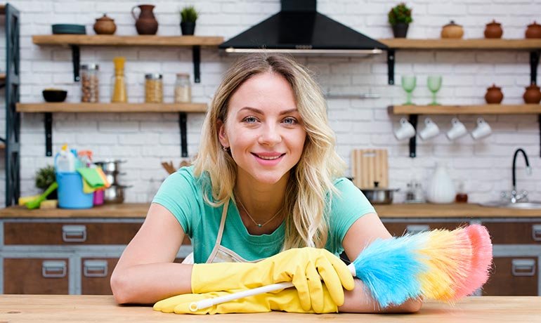 Schoonmaakmedewerker met plumeau in een keuken